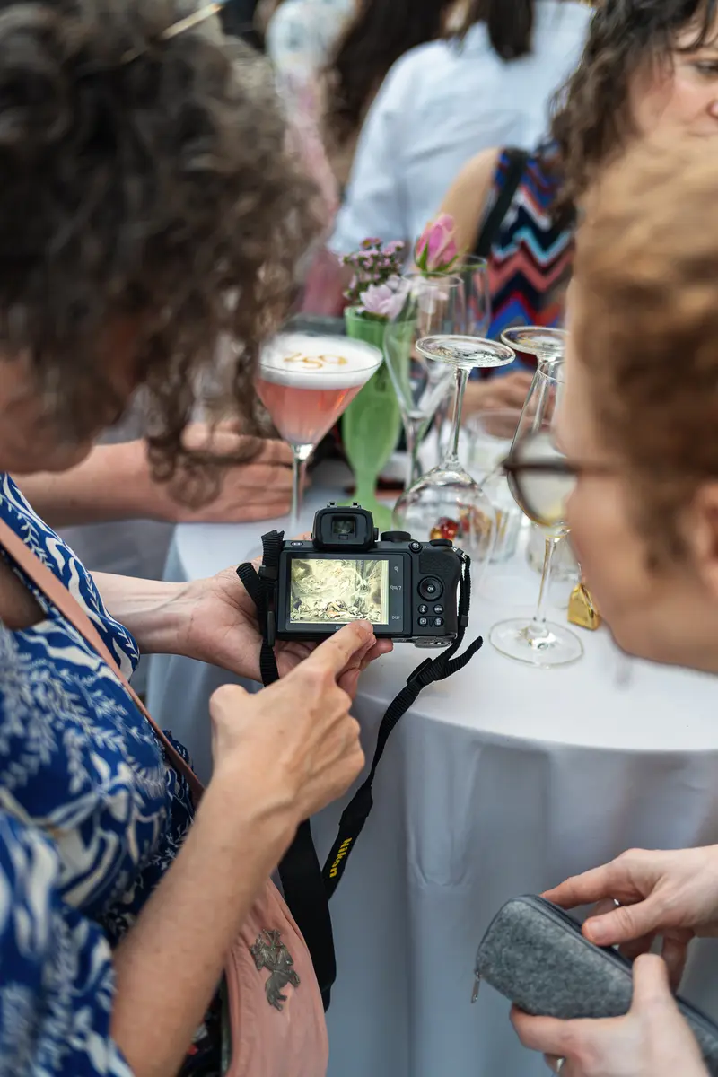 Guest Reviews Photo on Camera Screen at Social Event Reception