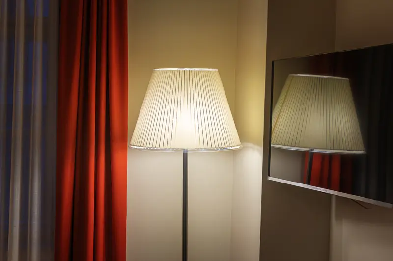 Lit floor lamp and flat-screen television in a Hotel Das Tigra guest room, Vienna