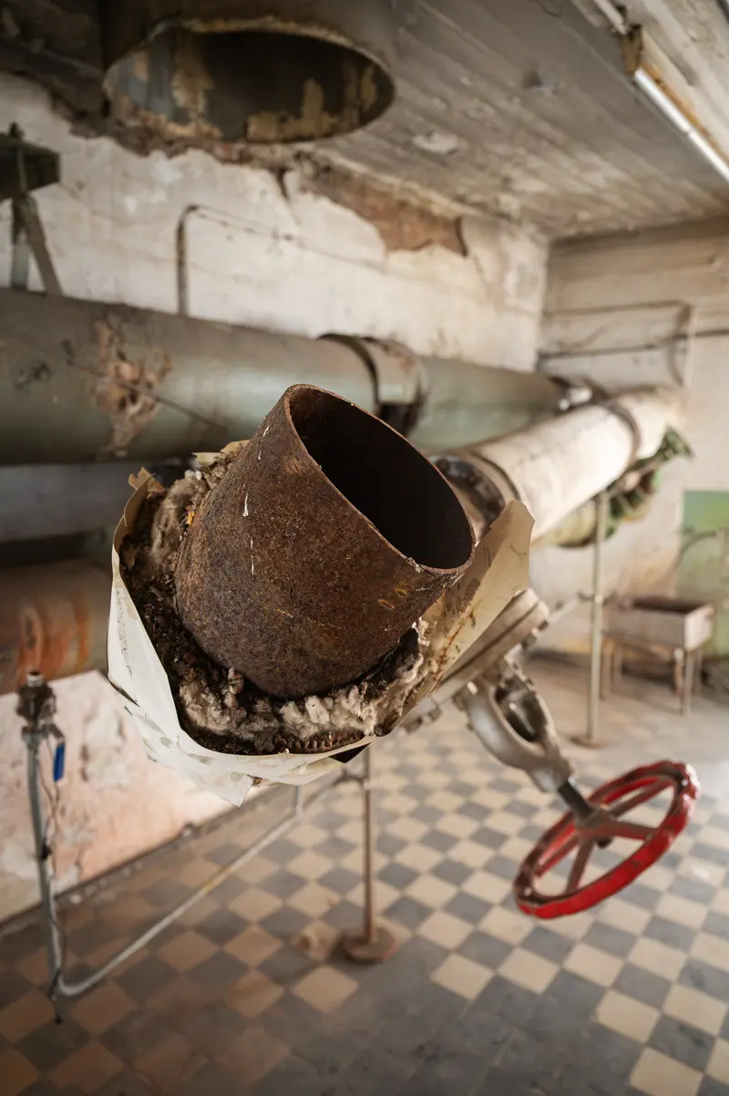 Severed insulated pipe and red valve wheel inside Glanzstoff factory, St. Pölten