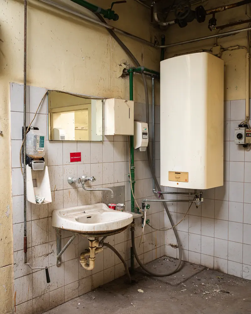 Disused washroom with wall-mounted boiler at Glanzstoff St. Pölten Open House 2026