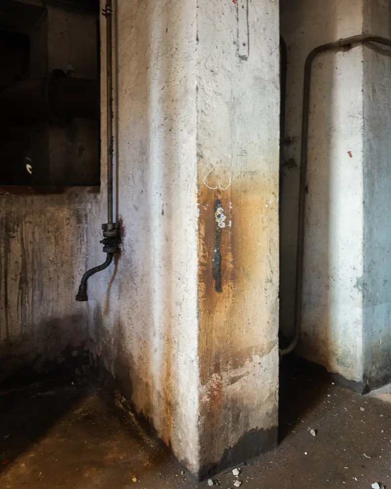Corroded concrete column and cast-iron pipework inside Glanzstoff factory hall, Open House 2026