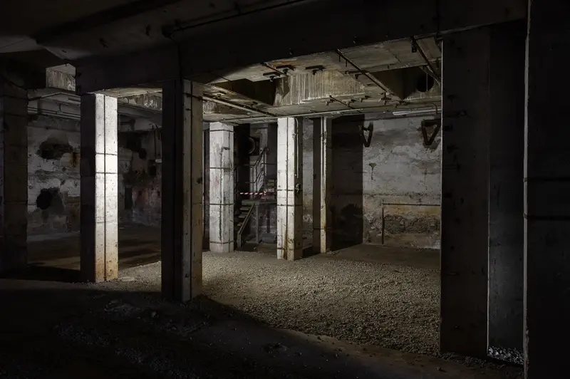 Unlit concrete cellar with mushroom columns and gravel floor, Glanzstoff St. Pölten Open House 2026
