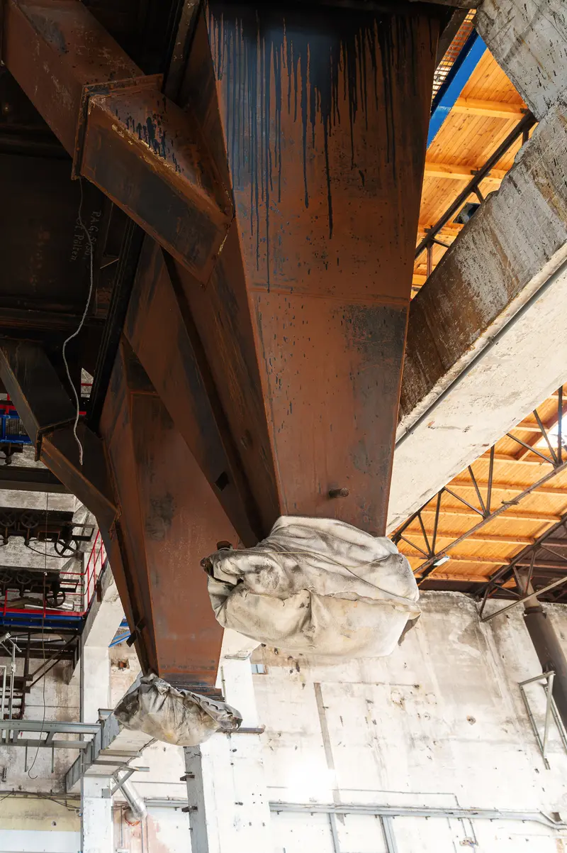Rusted steel crane girder and fabric sacks inside Glanzstoff St. Pölten factory hall